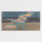 Abstract artwork with a blue chair and colorful steps on a beach.