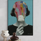 Framed abstract art print of a colorful head on a white wall with decorative vases and books below.