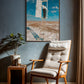 Chair with a plant and a framed artwork on a wall in a room.