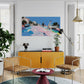Modern living room with yellow cabinet, brown chairs, and colorful abstract painting.