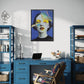 Modern home office with blue desk, chair, and shelves, featuring a colorful abstract art piece on the wall.