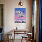 Room interior with a dining table and stools, colorful wall art, and a lamp.