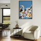 Modern living room with a white armchair, round table, and colorful abstract painting on the wall.