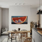 Modern kitchen with a dining area and a painting of an orange on the wall.