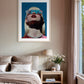 Framed artwork of a woman with sunglasses on a wall above a bed in a bedroom.