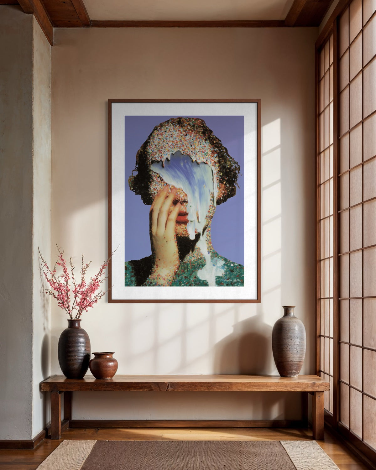 Framed artwork on a wall in a room with wooden bench and vases