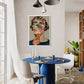 Dining room with a blue table and white chairs, featuring a colorful abstract painting on the wall.