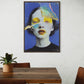 Framed abstract art of a face on a wall above a wooden table with chairs.