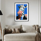 Framed artwork of a cow eating pizza on a wall above a beige sofa.