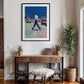 Framed artwork above a wooden console table with decorative items in a room.
