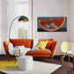 Modern living room with orange sofa, yellow rug, and abstract artwork on wall.