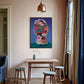 Room interior with a colorful abstract painting on the wall, wooden table, and stools.