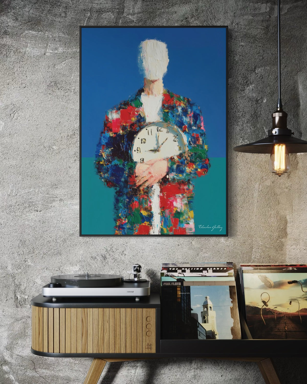 Framed abstract artwork of a person holding a clock on a wall above a record player and records.