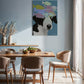 Dining room with a wooden table and chairs, featuring a colorful dog painting on the wall.