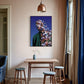 Room interior with a table, stools, and a colorful wall art piece.