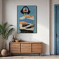 Framed artwork of a woman on a wall above a wooden sideboard in a room with a plant and door.