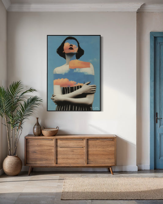 Framed artwork of a woman on a wall above a wooden sideboard in a room with a plant and door.