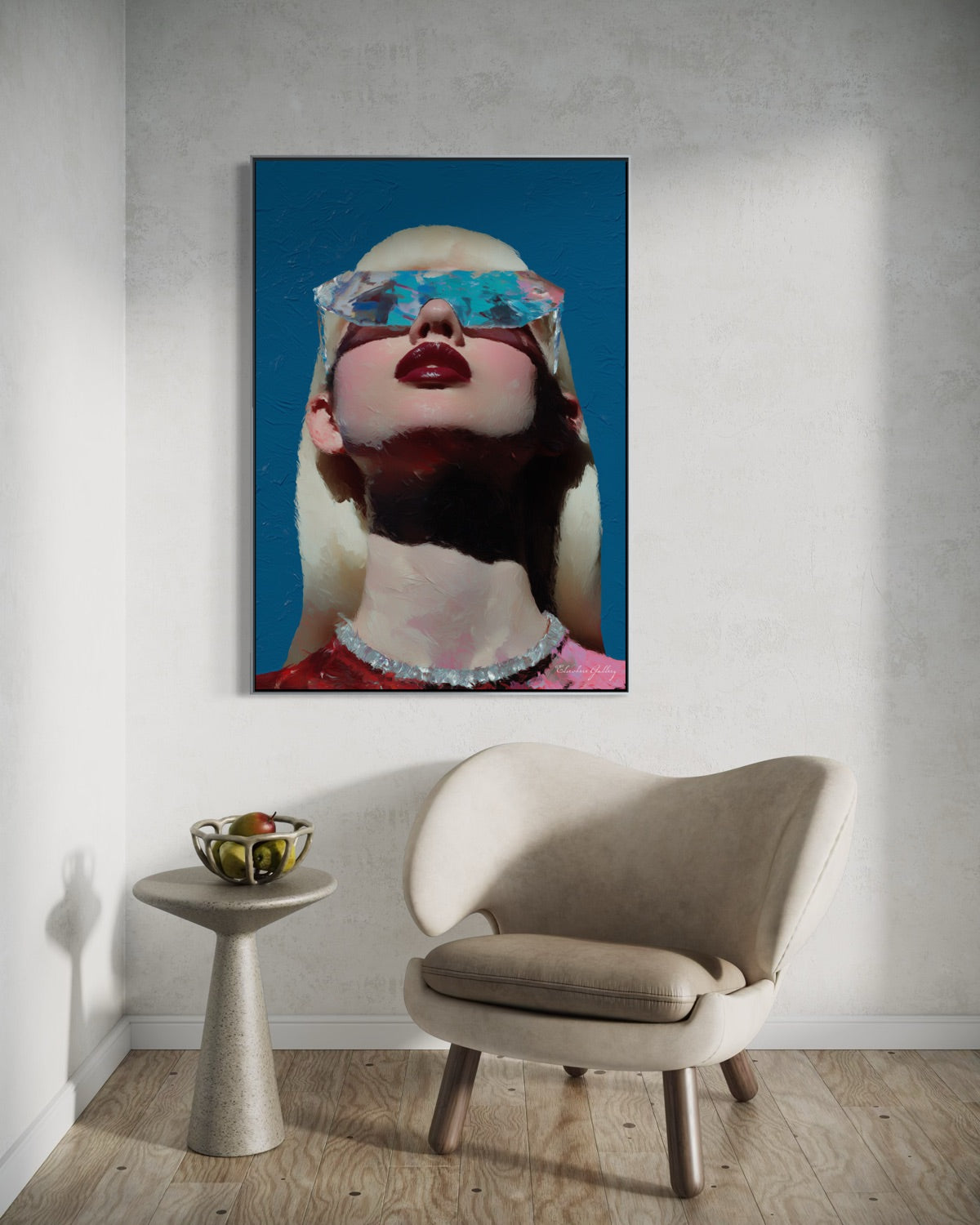Framed artwork of a stylized portrait on a wall above a chair and small table.