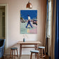 Room interior with a table, stools, and a colorful painting on the wall.