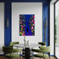 Modern dining room with a round table and green chairs, featuring a colorful abstract painting on the wall.