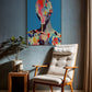 Colorful abstract painting on a wall above a wooden armchair in a room.