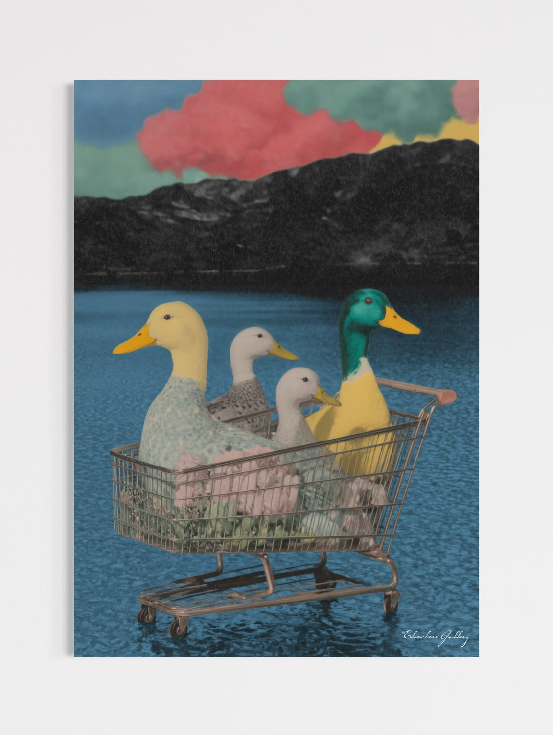 Surreal contemporary pop art print featuring four colorful ducks sitting inside a metal shopping cart floating on a blue lake, set against monochromatic mountains and vibrant sunset clouds, titled "Lost In The Ducks."